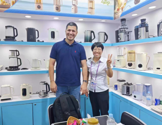 Zhongshan Yuekon Electrical Appliances Co., Limited のチームメンバーと海外の顧客が笑顔で集合写真を撮っている画像。これは前向きなビジネス交流を反映しています。