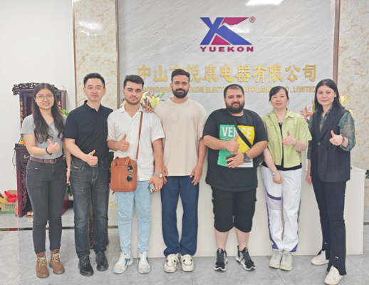 Zhongshan Yuekon Electrical Appliances Co., Limited の従業員と海外の顧客が一緒にポーズをとり、成功した協力的なビジネス関係を象徴しています。